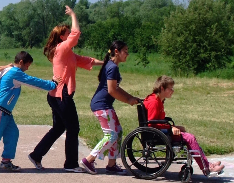 special needs kids walking behind a wheelchair